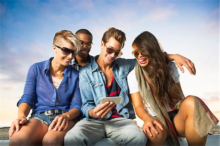 summer and phone and fun - Friends sitting on wall with smartphone, San Diego, California, USA Stock Photo - Premium Royalty-Free, Code: 614-07194859