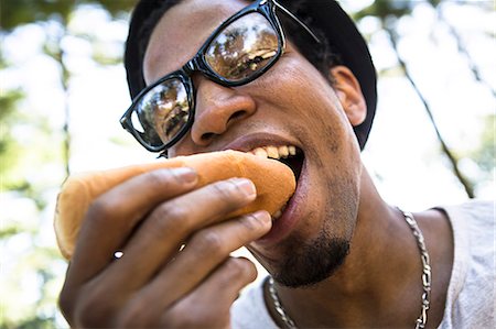 Young man eating bread roll Stock Photo - Premium Royalty-Free, Code: 614-07234899