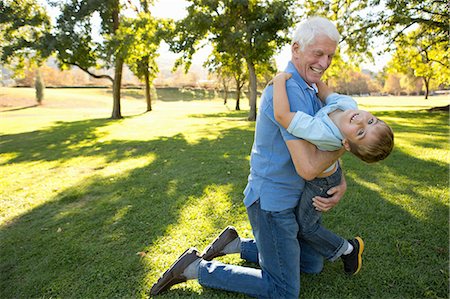 family with grandparents active - Grandfather kneeling on grass hugging grandson Stock Photo - Premium Royalty-Free, Code: 614-07235014