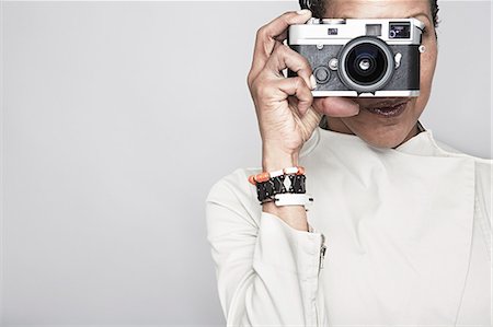 Studio portrait of mature woman holding up camera Stock Photo - Premium Royalty-Free, Code: 614-07240015