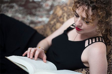 Portrait of young woman reclining and reading book Stock Photo - Premium Royalty-Free, Code: 614-07240103