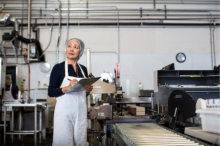 senior woman alone thinking - Factory worker making notes on clipboard by production line Stock Photo - Premium Royalty-Free, Code: 614-07240160