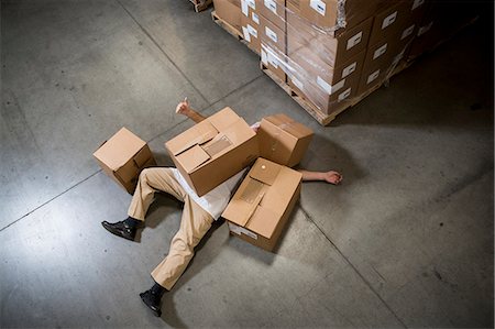 dead - Man lying on floor covered by cardboard boxes in warehouse Foto de stock - Sin royalties Premium, Código: 614-07240170