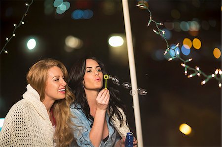 Two female friends blowing bubbles at rooftop party Foto de stock - Sin royalties Premium, Código: 614-07240207