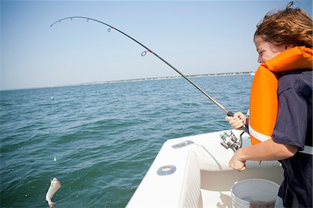 Boy catching fish from boat,  Falmouth, Massachusetts, USA Photographie de stock - Premium Libres de Droits, Code: 614-07444056