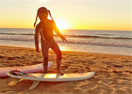 surfboard beach - Young girl at beach wearing wetsuit and standing on surfboard Stock Photo - Premium Royalty-Free, Code: 614-07444104