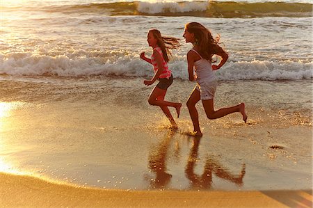 pacific girls photo - Two girls running along beach at sunset Stock Photo - Premium Royalty-Free, Code: 614-07444103