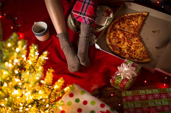 Young woman's legs amongst christmas gifts and pizza box Stock Photo - Premium Royalty-Free, Image code: 614-07444154