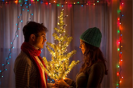 festive lights at night - Young couple holding illuminated christmas tree Stock Photo - Premium Royalty-Free, Code: 614-07444168