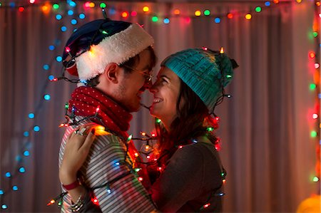 Romantic young couple wrapped in decorative lights at christmas Stock Photo - Premium Royalty-Free, Code: 614-07444161