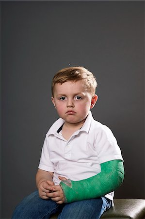 Portrait of sullen young boy with plaster cast on arm Stock Photo - Premium Royalty-Free, Code: 614-07444247