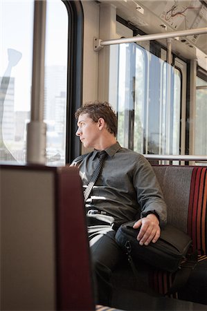 Mid adult businessman looking out of train carriage window Fotografie stock - Premium Royalty-Free, Codice: 614-07444249