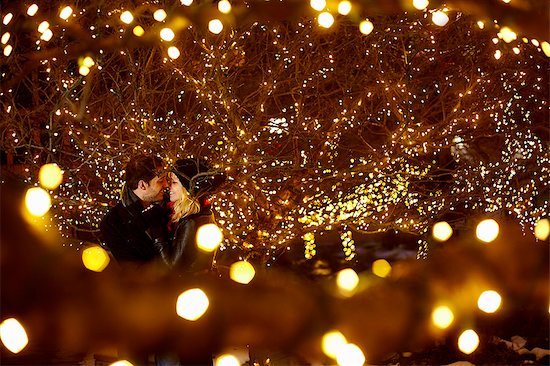 Young couple kissing surrounded by city xmas lights Stock Photo - Premium Royalty-Free, Image code: 614-07444256