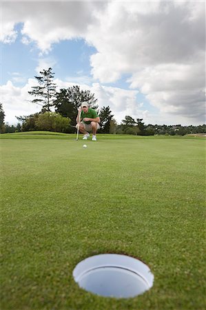 Young male golfer lining up the ball on the green Stock Photo - Premium Royalty-Free, Code: 614-07444275