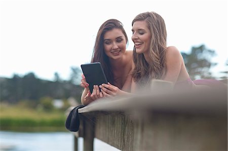 smile relaxed - Two young women on river pier looking at digital tablet Stock Photo - Premium Royalty-Free, Code: 614-07444307