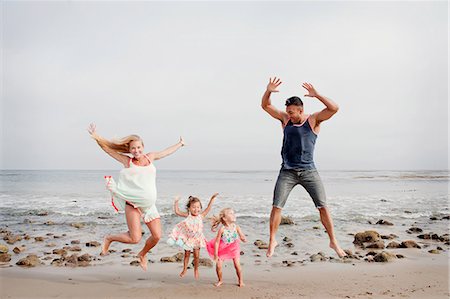 family life - Parents and two young girls jumping mid air on beach Stock Photo - Premium Royalty-Free, Code: 614-07444318