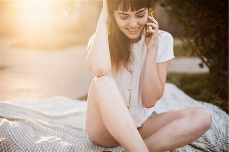 smartphone, outside - Young woman sitting on picnic blanket talking on cellphone Stock Photo - Premium Royalty-Free, Code: 614-07444335