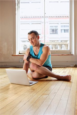 symbols for computer - Mid adult man using laptop whilst in Cowface yoga pose Stock Photo - Premium Royalty-Free, Code: 614-07444346