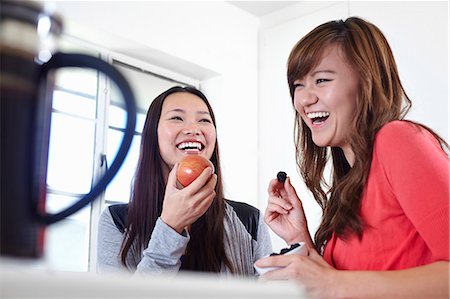 Two young women in kitchen eating fruit Foto de stock - Sin royalties Premium, Código: 614-07443999