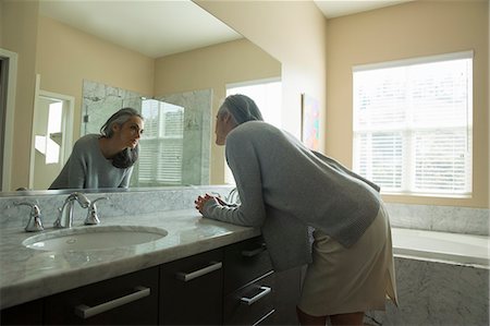 sunlight mature indoors - Woman pondering in front of mirror Stock Photo - Premium Royalty-Free, Code: 614-07453271