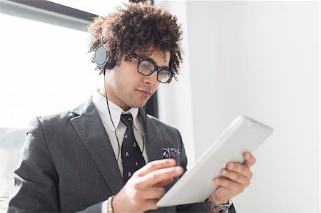 Young man wearing headphones using digital tablet Stock Photo - Premium Royalty-Free, Code: 614-07487049