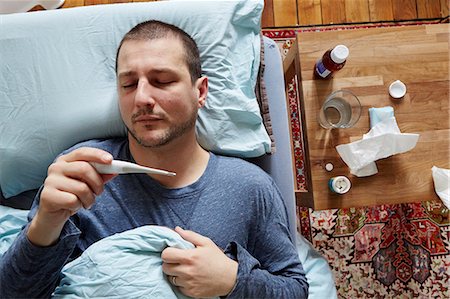 Mid adult man lying in bed looking at thermometer reading Foto de stock - Sin royalties Premium, Código: 614-07487159