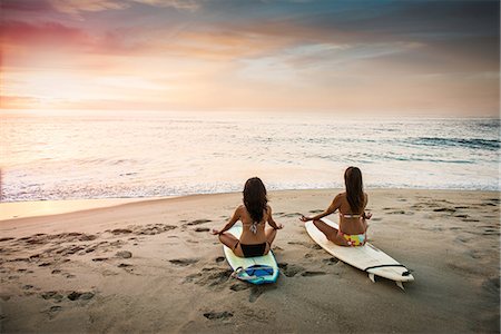 swimwear back woman - Two surfers, sitting on surfboards on beach, meditating Photographie de stock - Premium Libres de Droits, Code: 614-07487181