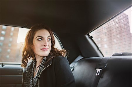 Young woman looking back from taxi Stock Photo - Premium Royalty-Free, Code: 614-07487258