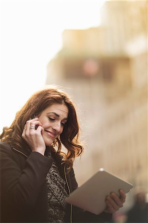 Young woman using cellphone and digital tablet on street Stock Photo - Premium Royalty-Free, Code: 614-07487252