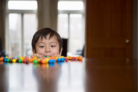 dulces - Boy peering over table at candy Foto de stock - Sin royalties Premium, Código: 614-07587639