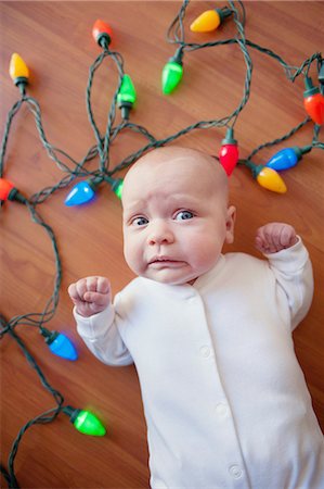 funny pictures - Baby lying on floor surrounded by christmas lights Foto de stock - Sin royalties Premium, Código: 614-07587633
