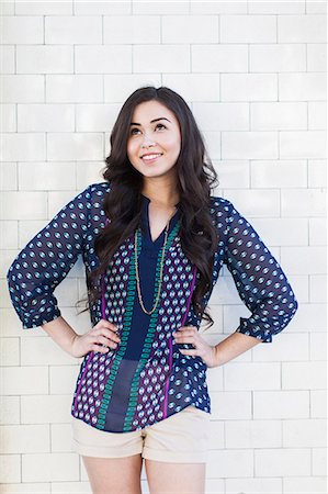 smiling looking up - Young woman standing with hands on hips Stock Photo - Premium Royalty-Free, Code: 614-07587649