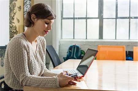 smartphone laptop - Young female designer texting on smartphone in design studio Photographie de stock - Premium Libres de Droits, Code: 614-07587720