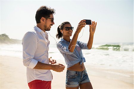 Couple sharing music from smartphone, Arpoador beach, Rio De Janeiro, Brazil Stock Photo - Premium Royalty-Free, Code: 614-07652221