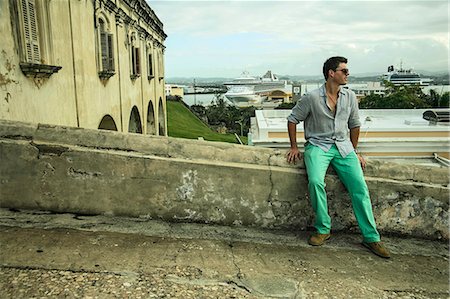 Young man sitting on wall next to Castillo San Felipe del Morro, Old San Juan, Puerto Rico Stock Photo - Premium Royalty-Free, Code: 614-07652230