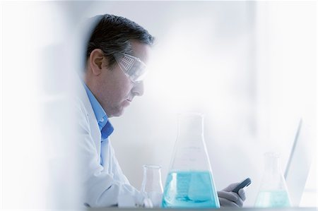 science experiment - Scientist looking at smartphone Stock Photo - Premium Royalty-Free, Code: 614-07652260