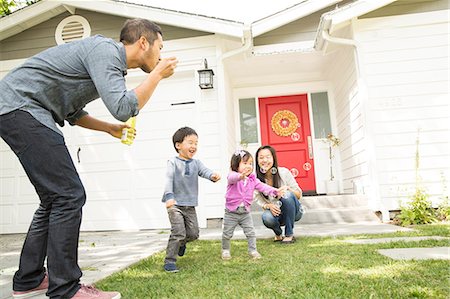 Mid adult couple with two children blowing bubbles Photographie de stock - Premium Libres de Droits, Code: 614-07652355