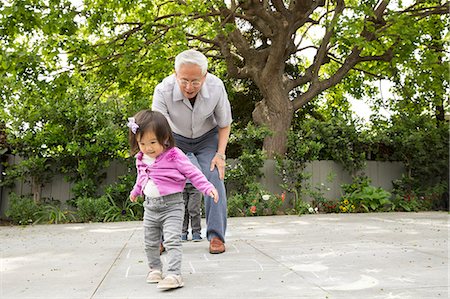 Grandfather playing hopscotch with toddler granddaughter Foto de stock - Sin royalties Premium, Código: 614-07652359