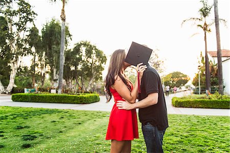 Couple kissing behind mortarboard Foto de stock - Royalty Free Premium, Número: 614-07652370