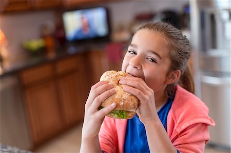 sandwich photography - Girl in kitchen biting sandwich Stock Photo - Premium Royalty-Free, Code: 614-07652479