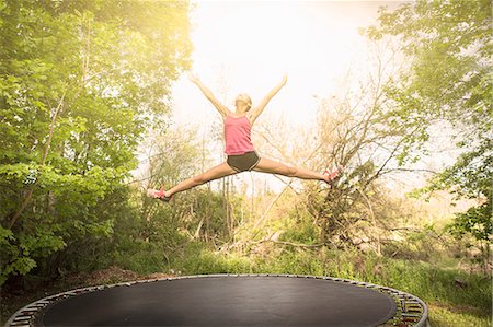 enjoy girl - Teenage girl doing star jump on trampoline, outdoors Stock Photo - Premium Royalty-Free, Code: 614-07708258