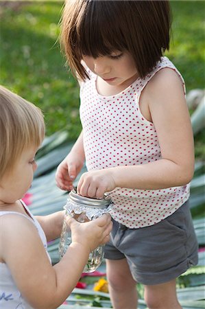 siblings blond - Girl and toddler sister holding jar with green anole lizard in garden Stock Photo - Premium Royalty-Free, Code: 614-07708250