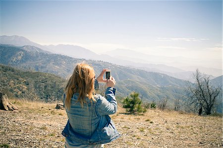 Rear view of mid adult woman photographing view on smartphone, Lake Arrowhead, California, USA Stock Photo - Premium Royalty-Free, Code: 614-07708321