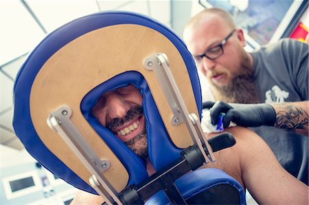 Male customers face between headrest in tattoo parlor Fotografie stock - Premium Royalty-Free, Codice: 614-07735143