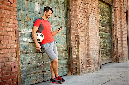 Young male soccer player texting on smartphone Stock Photo - Premium Royalty-Free, Code: 614-07735153