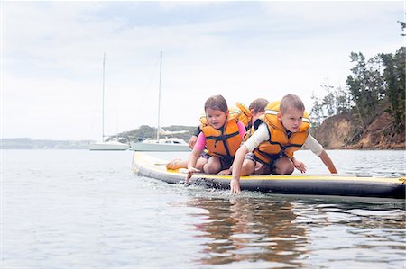 simsearch:614-07735202,k - Brothers and sister paddleboarding on knees at sea Stock Photo - Premium Royalty-Free, Code: 614-07735212