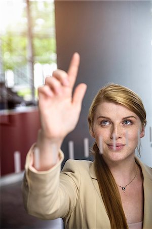simsearch:614-07708118,k - Young businesswoman writing message on glass wall with finger Stock Photo - Premium Royalty-Free, Code: 614-07735229