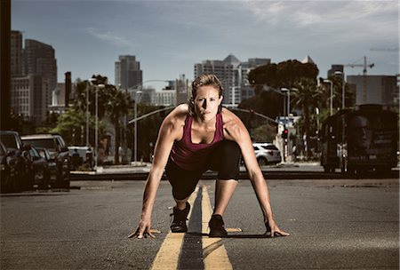 Young adult woman in start position in road, getting ready to run Stockbilder - Premium RF Lizenzfrei, Bildnummer: 614-07735293