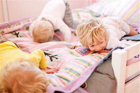 Three young brothers crawling face down on bed Stock Photo - Premium Royalty-Free, Code: 614-07735307