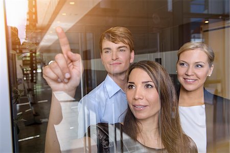 Businesswoman pointing out of glass window to colleagues Stock Photo - Premium Royalty-Free, Code: 614-07735322